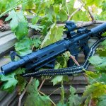 Two point paracord gun sling on a rifle. Primary color woodland camo. Secondary color black. Double cobra weave.