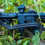 Two point paracord gun sling on a rifle. Primary color grey. Secondary color black. Double cobra weave.