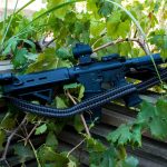 Two point paracord gun sling on a rifle. Primary color grey. Secondary color black. Double cobra weave.